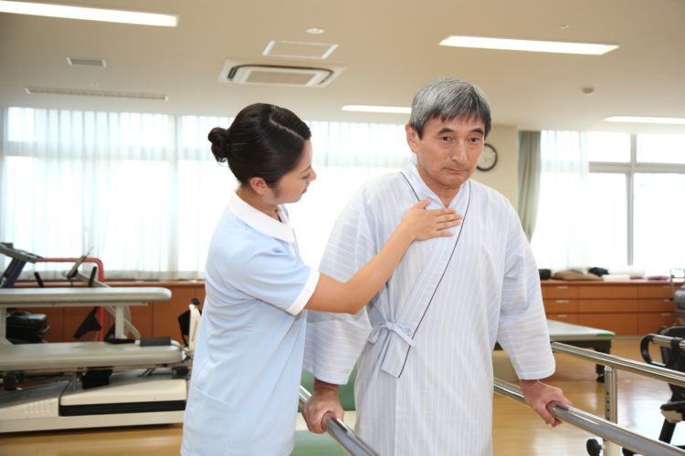 視床出血の後遺症である歩行障害のリハビリをする高齢男性
